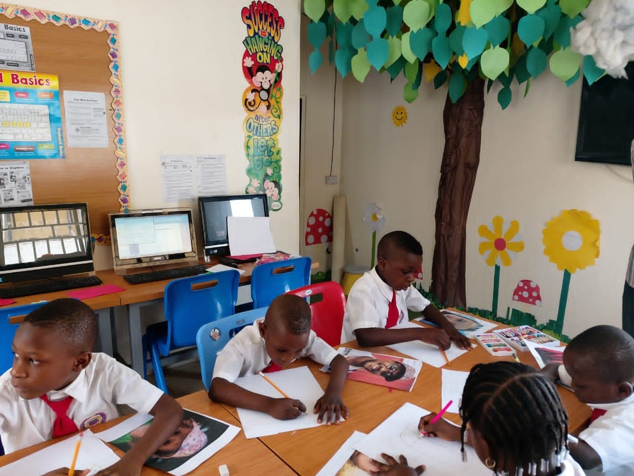 Pupils working at their desks in a classroom decorated with a paper tree display